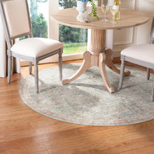 Load image into Gallery viewer, Round area rug under a dining table with chairs in a room with large windows.