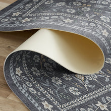 Load image into Gallery viewer, Floral patterned rug being rolled out on a wooden floor