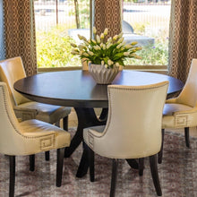 Load image into Gallery viewer, Dining room with a round dark wood table and beige chairs, featuring a vase of white flowers placed on a round mat.