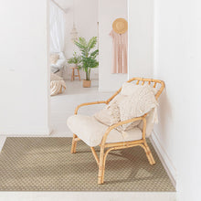 Load image into Gallery viewer, Rattan chair with beige cushion on a textured rug in a bright room.