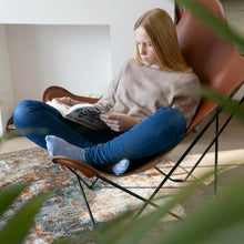 Load image into Gallery viewer, Woman reading a book in a chair with a plant in the foreground