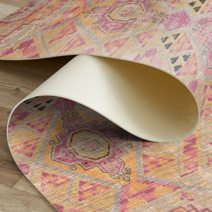 Close-up of a patterned rug being rolled out on a wooden floor.