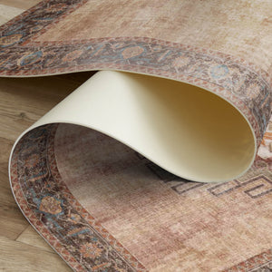 Close-up of a beige chair on a patterned rug with wooden floor underneath
