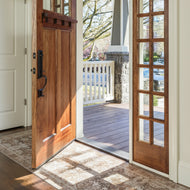 Wooden front door with glass panels open to a porch and farmhouse vinyl rug