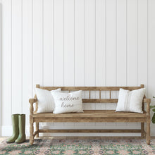 Load image into Gallery viewer, Wooden bench with decorative pillows against a white paneled wall.
