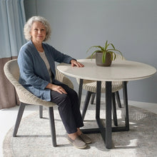 Load image into Gallery viewer, Woman sitting at a modern dining table in a home setting and a beautiful, round area vinyl mat
