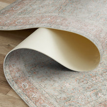 Load image into Gallery viewer, Close-up of a patterned rug with a beige chair leg partially visible
