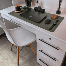 Load image into Gallery viewer, A dark olive green desk mat with the brand name 'KELLY' printed on it, styled on a white desk with a laptop, mouse, mug, and chair placed on a vinyl desk mat
