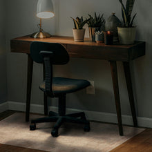 Load image into Gallery viewer, A dark wood writing desk with tapered legs and a black office chair in a dimly lit home office setting, decorated with potted plants, a table lamp, and a textured vase.
