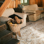 Living room with checkered chairs, a wicker basket with pinecones, and a floral rug.
