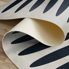 Load image into Gallery viewer, Close-up of a patterned rug with black and beige design on a wooden floor.
