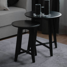 Load image into Gallery viewer, Two black side tables with cylindrical objects on a light-colored rug.
