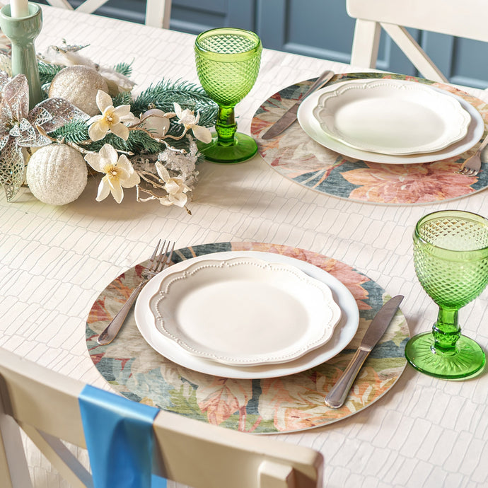 Decorative table setting with green glasses, floral centerpieces, and patterned placemats.