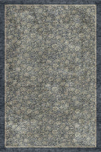 Load image into Gallery viewer, A rectangular area rug with a distressed, vintage-style floral pattern in muted beige, gray, and navy blue tones, featuring a solid dark border.

