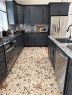 A long rectangular area rug with a beige background and a floral pattern in blue, brown, and gray, shown in a modern kitchen setting.