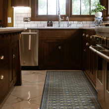 Load image into Gallery viewer, A long rectangular runner rug with a blue, beige, and gray geometric pattern is styled on a light marble tile kitchen floor between dark wood cabinets.
