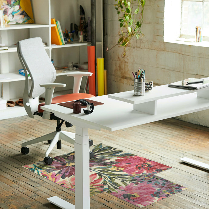 Modern office setup with a white desk, chair, and colorful rug on wooden floor.