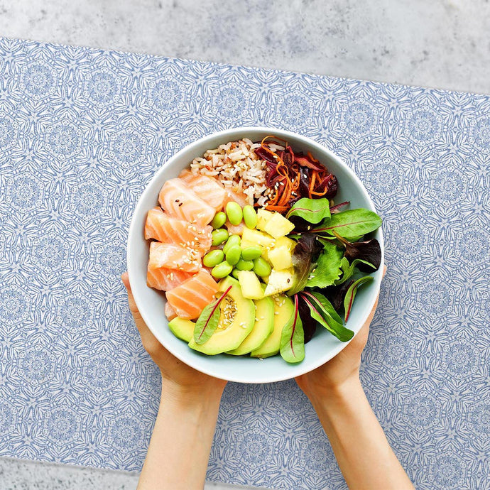 Poke bowl served on blue pattern placemat 
