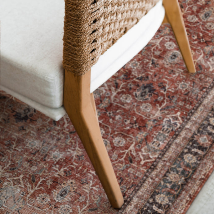 Patterned rug with a chair on top, showcasing intricate designs.