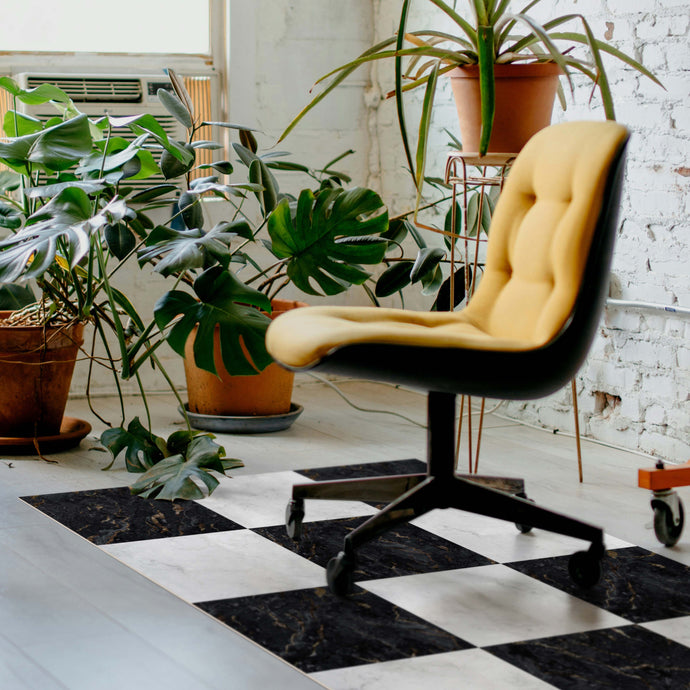 Yellow chair in a room with plants and a checkered floor