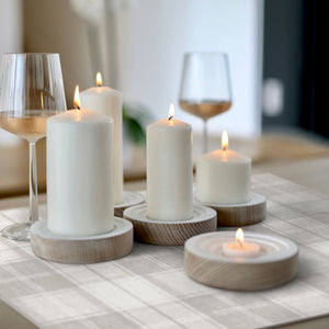 Candlelit table setting with glasses of wine on a checkered tablecloth.