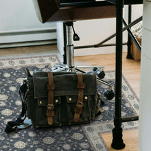 Load image into Gallery viewer, Waxed canvas bag with leather straps on a patterned chair mat
