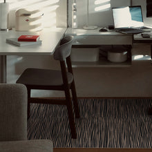 Load image into Gallery viewer, A modern home office scene featuring a white L-shaped desk with a dark gray upholstered chair, a laptop on top, and a striped desk mat on the floor.
