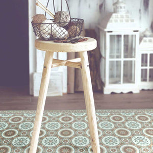 Brown and green vintage vinyl floor mat with Spanish tile designs under a stool chair